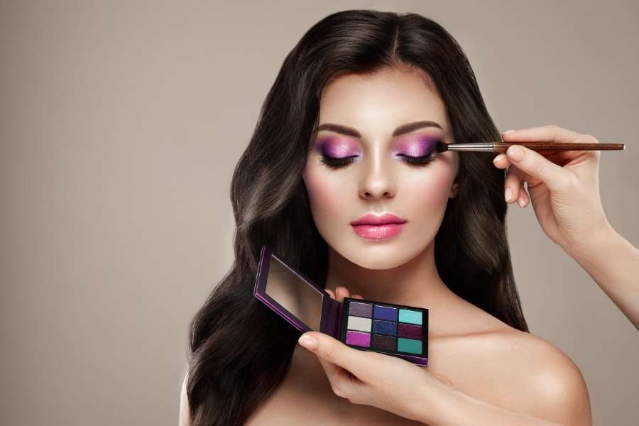 Une femme reçoit une application de maquillage des yeux violet pour un effet agrandissant.