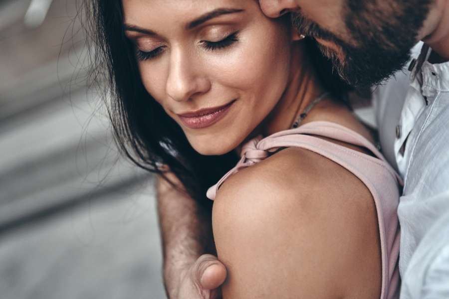 Un homme embrasse tendrement une femme qui sourit les yeux fermés.